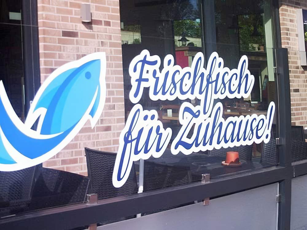 Schriftzug 'Frischfisch für Zuhause!' auf einem Fenster eines Restaurants oder Fischgeschäfts